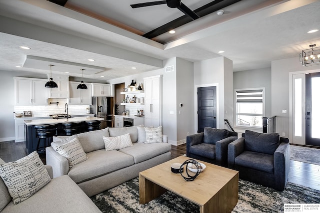 living area featuring recessed lighting, baseboards, a raised ceiling, and dark wood finished floors