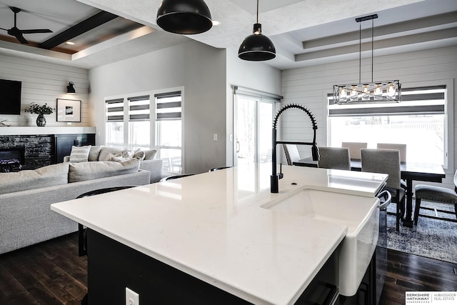 kitchen featuring a tray ceiling, wooden walls, and dark wood-style flooring