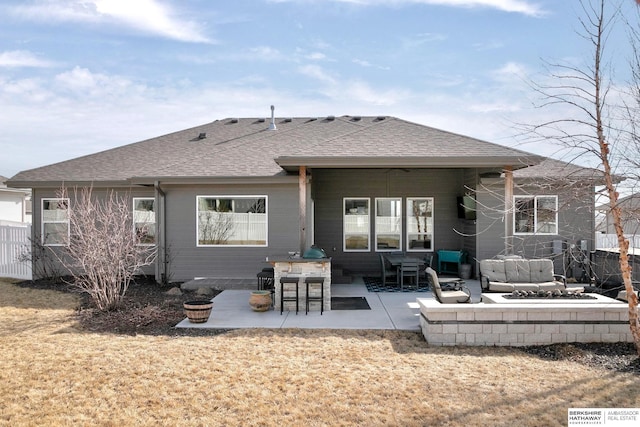 rear view of property featuring a patio, fence, and a shingled roof