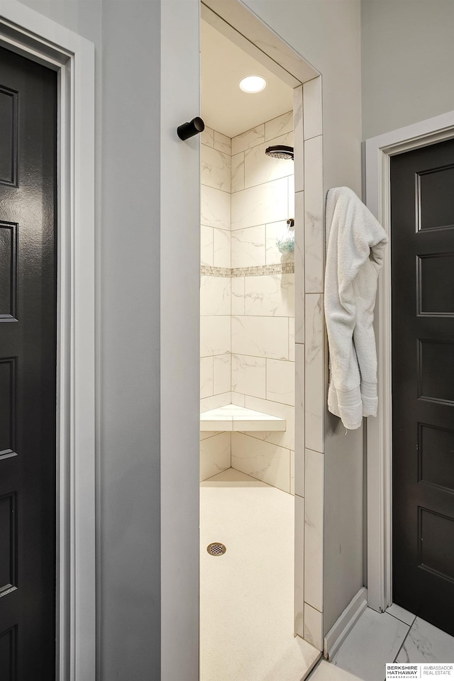 full bath featuring marble finish floor and a tile shower