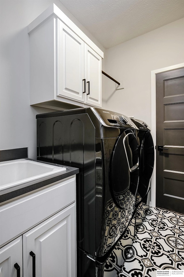 clothes washing area featuring tile patterned floors, cabinet space, a textured ceiling, and independent washer and dryer