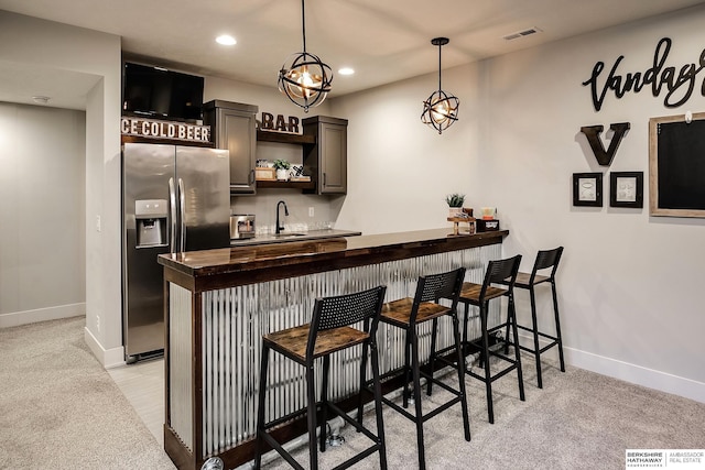 bar featuring visible vents, indoor wet bar, recessed lighting, stainless steel refrigerator with ice dispenser, and a sink