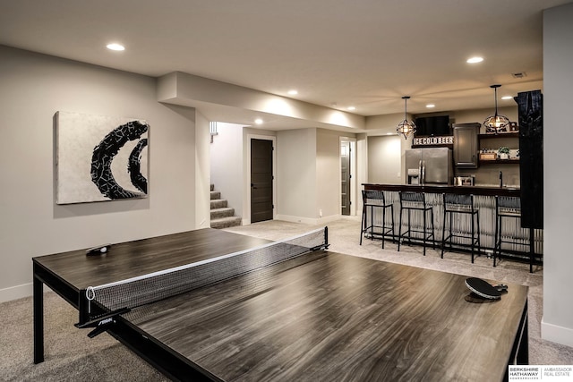 rec room featuring recessed lighting, indoor wet bar, baseboards, and light carpet