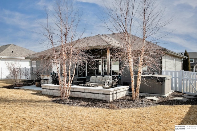 back of property featuring a yard, fence, and a hot tub