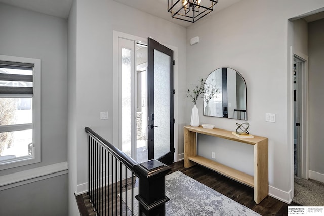 entryway featuring a notable chandelier, dark wood-type flooring, and baseboards