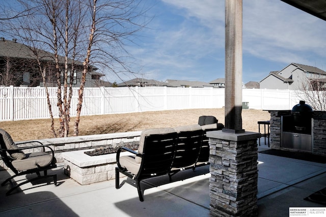 view of patio featuring area for grilling, a fenced backyard, and an outdoor fire pit