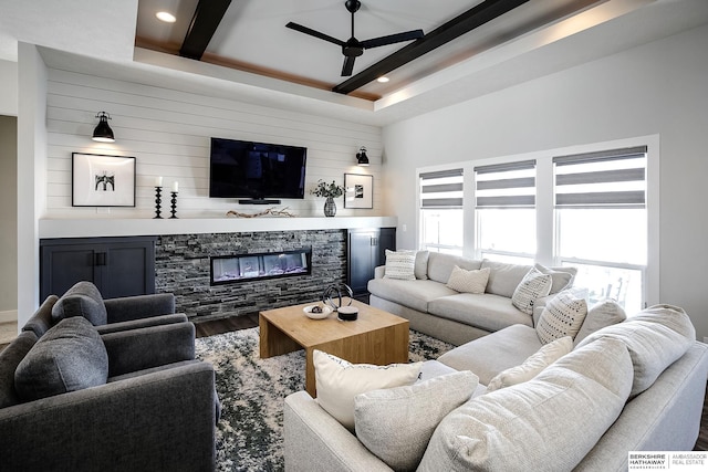 living area with a tray ceiling, recessed lighting, a fireplace, wood finished floors, and a ceiling fan