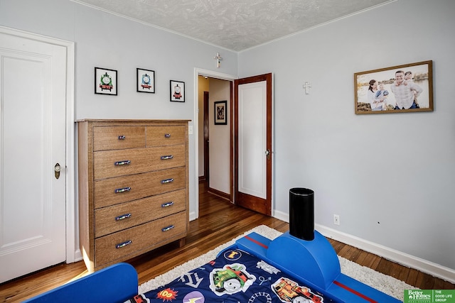 bedroom featuring baseboards, a textured ceiling, and wood finished floors