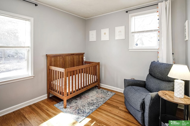 bedroom with baseboards, multiple windows, and wood finished floors