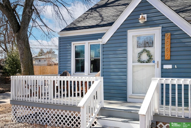 property entrance with a wooden deck and a shingled roof