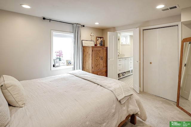 bedroom with visible vents, light carpet, recessed lighting, a closet, and ensuite bath