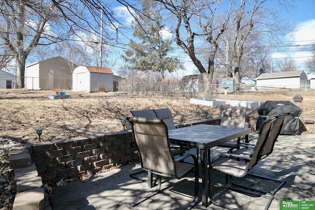 view of patio / terrace featuring a shed, outdoor dining area, a fenced backyard, an outbuilding, and a grill