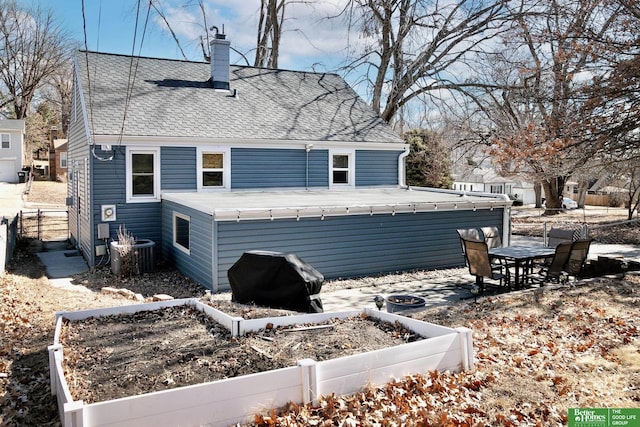 view of side of property featuring a shingled roof, fence, central air condition unit, a chimney, and a garden