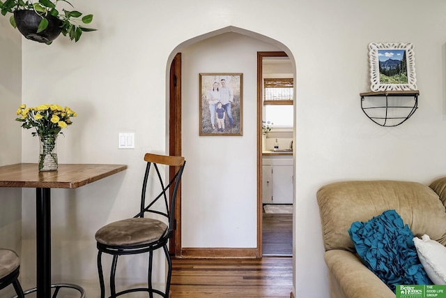 interior space featuring arched walkways, baseboards, and dark wood-style flooring