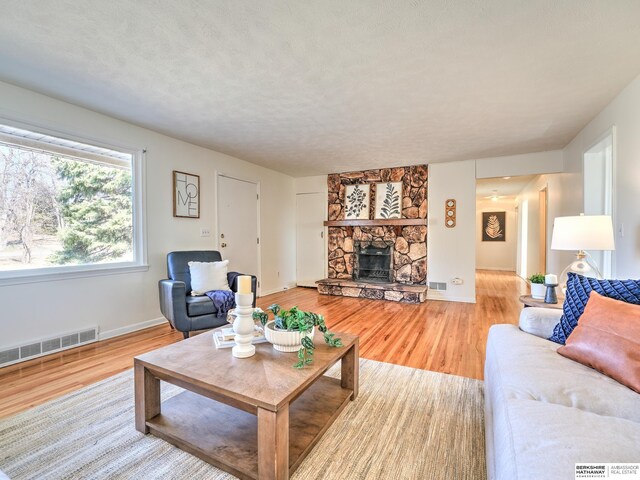 living area featuring visible vents, baseboards, a fireplace, and light wood finished floors