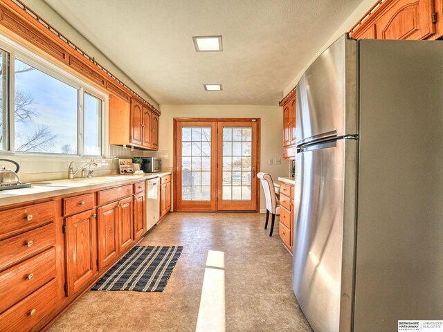 kitchen with a wealth of natural light, light countertops, freestanding refrigerator, and white dishwasher