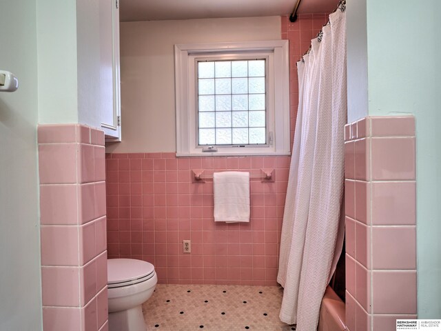 bathroom featuring curtained shower, toilet, tile walls, and a wainscoted wall