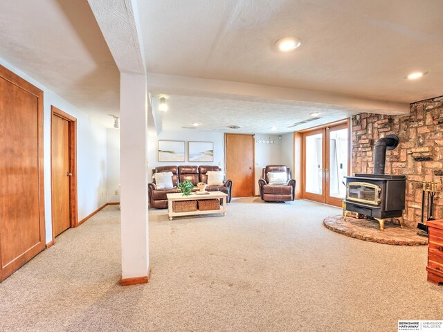 living room with french doors, a textured ceiling, a wood stove, and carpet