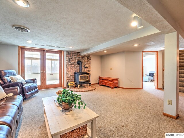 carpeted living area with a textured ceiling, stairs, french doors, baseboards, and a wood stove