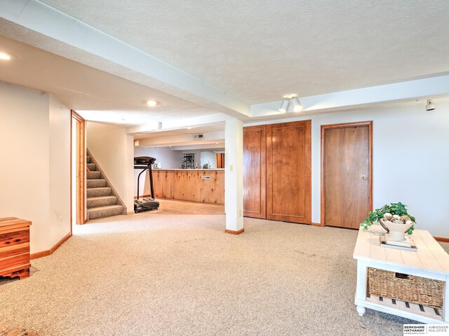 interior space featuring a textured ceiling, recessed lighting, carpet floors, baseboards, and stairs