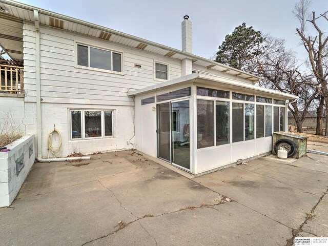 back of house featuring a patio area, a sunroom, and a chimney