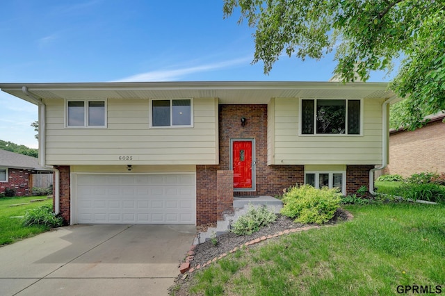 bi-level home featuring concrete driveway, a garage, brick siding, and a front lawn