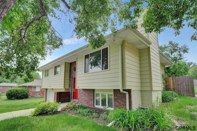 split foyer home with brick siding, a front lawn, and fence