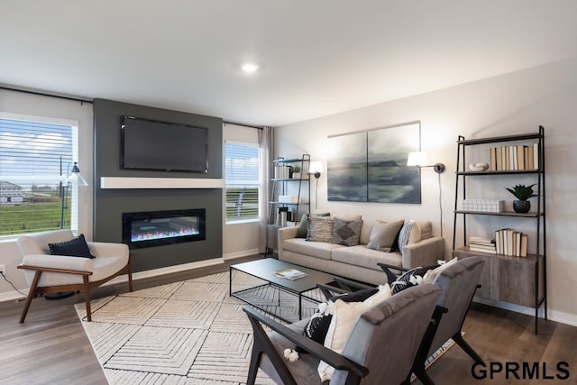 living room with a glass covered fireplace, wood finished floors, and baseboards