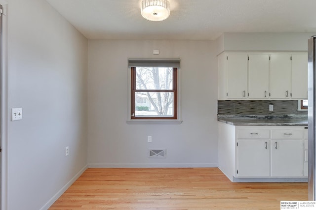 kitchen with visible vents, baseboards, light wood-style floors, white cabinetry, and tasteful backsplash