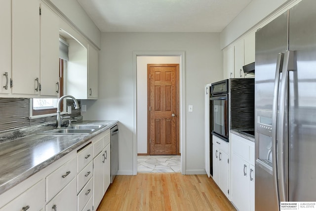 kitchen featuring white cabinetry, light wood-style floors, appliances with stainless steel finishes, and a sink