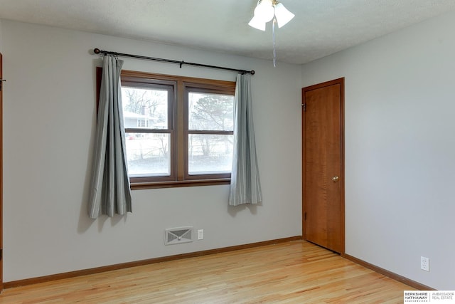 unfurnished room featuring light wood-style flooring, visible vents, baseboards, and a textured ceiling