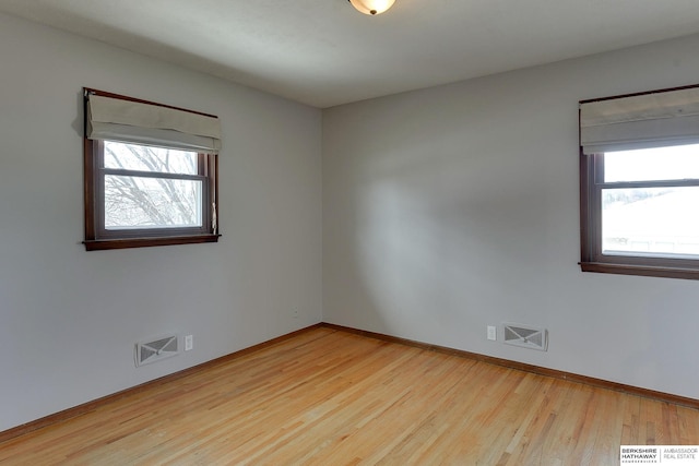 unfurnished room featuring visible vents, a healthy amount of sunlight, and wood finished floors