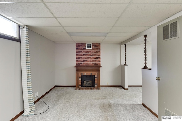 unfurnished living room featuring baseboards, visible vents, carpet floors, a paneled ceiling, and a brick fireplace