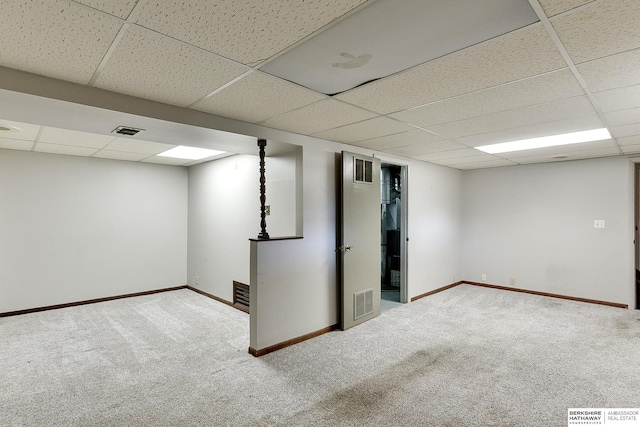 finished below grade area with a drop ceiling, visible vents, carpet floors, and baseboards