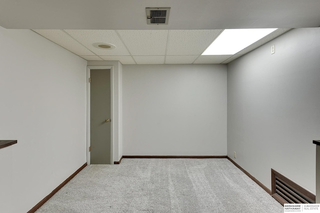 spare room with a drop ceiling, visible vents, baseboards, and carpet floors