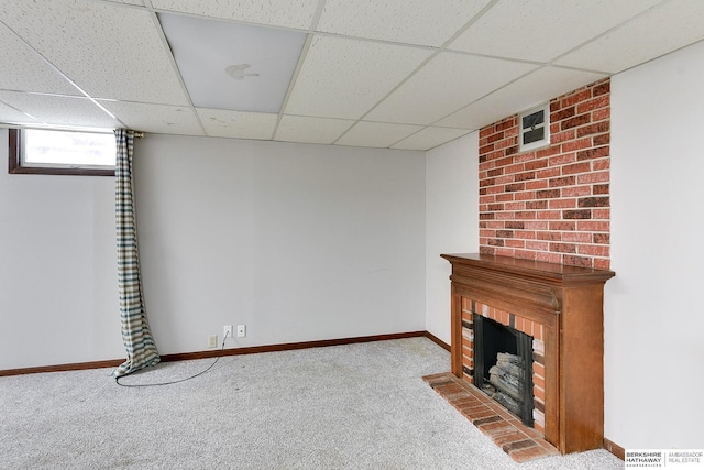 unfurnished living room with a drop ceiling, a fireplace, baseboards, and carpet