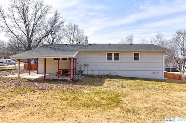 back of property with a patio, fence, roof with shingles, a carport, and a lawn