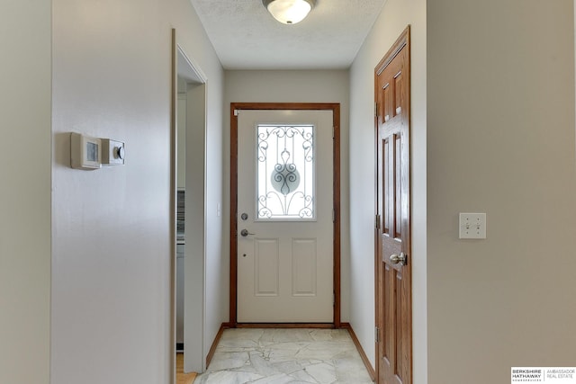 doorway to outside with marble finish floor, a textured ceiling, and baseboards