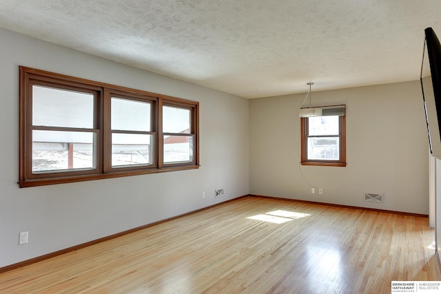 empty room featuring visible vents, a textured ceiling, and wood finished floors