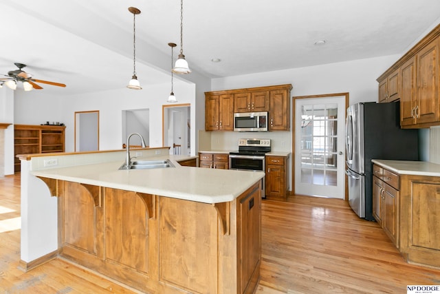 kitchen with light wood-style flooring, brown cabinetry, appliances with stainless steel finishes, and a sink