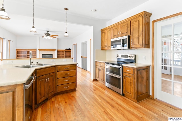 kitchen with a sink, brown cabinetry, light wood-type flooring, and stainless steel appliances