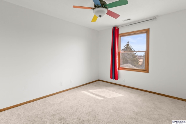 carpeted spare room with visible vents, a ceiling fan, and baseboards