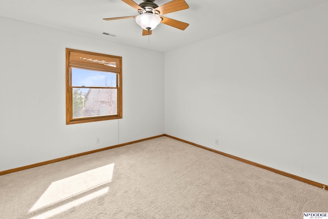 spare room with a ceiling fan, baseboards, visible vents, and light carpet