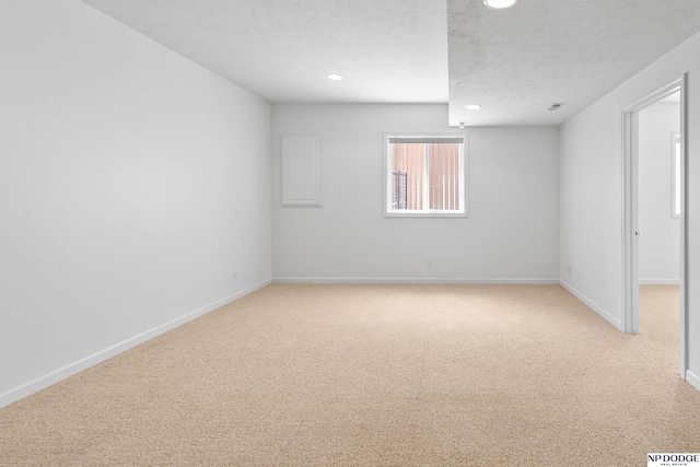 spare room with recessed lighting, baseboards, light colored carpet, and a textured ceiling