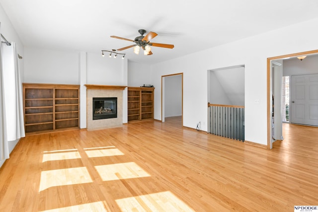 unfurnished living room featuring a ceiling fan, wood finished floors, and a tile fireplace