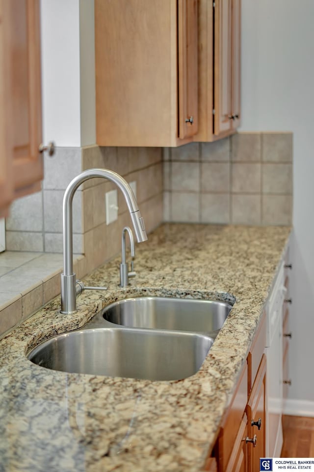 interior details featuring light stone counters, backsplash, and a sink