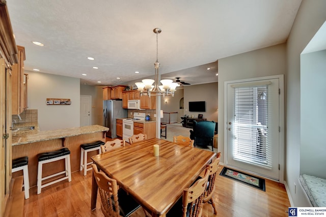 dining space with an inviting chandelier, light wood-style flooring, and recessed lighting