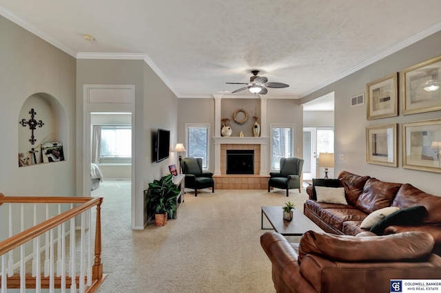 living room featuring visible vents, carpet floors, a tiled fireplace, and crown molding