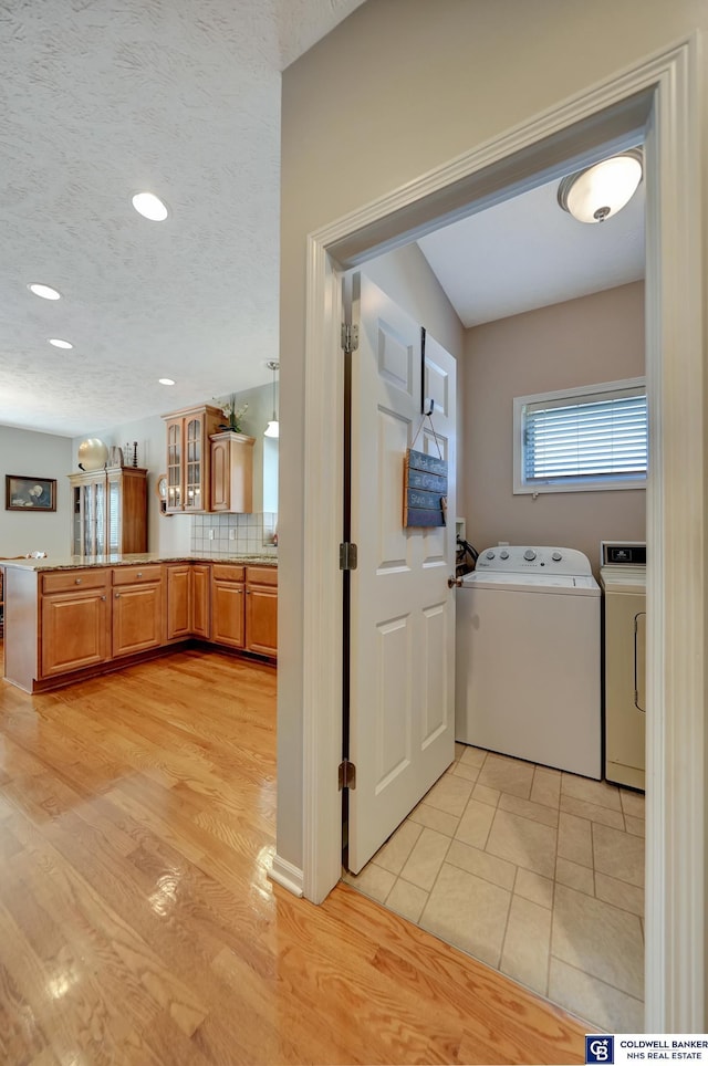 laundry area with a textured ceiling, recessed lighting, light wood-style floors, separate washer and dryer, and laundry area