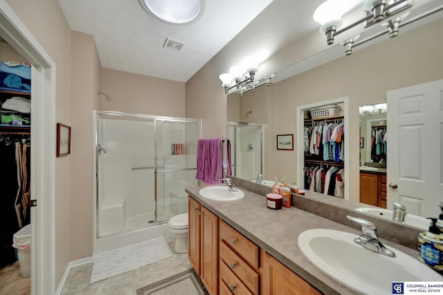 full bathroom featuring double vanity, visible vents, a stall shower, and a sink